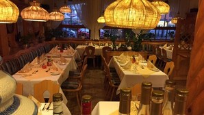 Un restaurante con varias mesas preparadas para comer, mostrando una variedad de botellas y vasos sobre ellas.