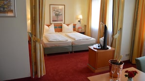 Una habitación de hotel con una cama, un escritorio con ordenador, televisión y minibar.