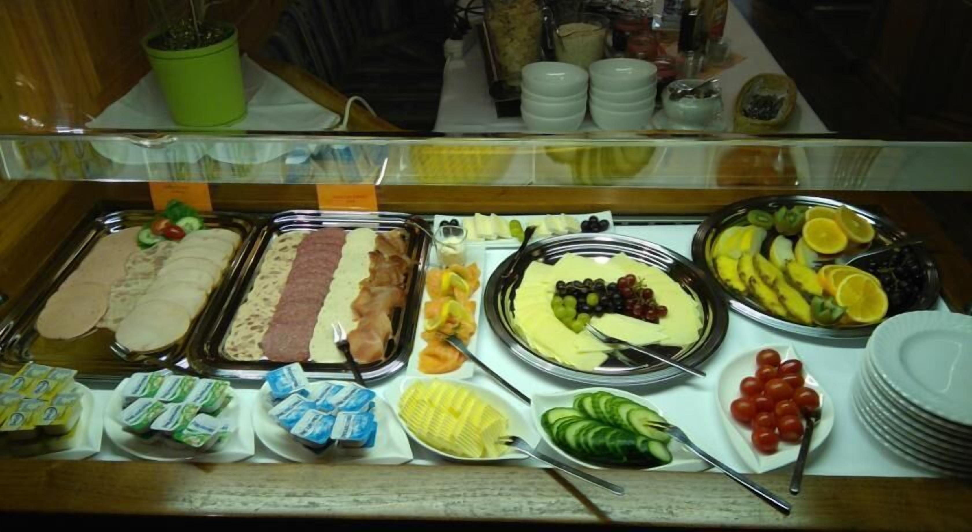 Ein reichhaltiges Buffet mit verschiedenen Speisen, darunter Fleisch-, Käse-, Obst- und Gemüsesorten.