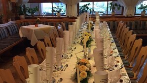 Una larga mesa de comedor dispuesta con manteles blancos, velas y centros de mesa florales.
