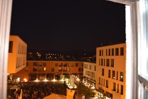 A nighttime view of a cityscape with buildings and a crowd of people in the foreground. - Arkaden Hotel (Kelkheim)