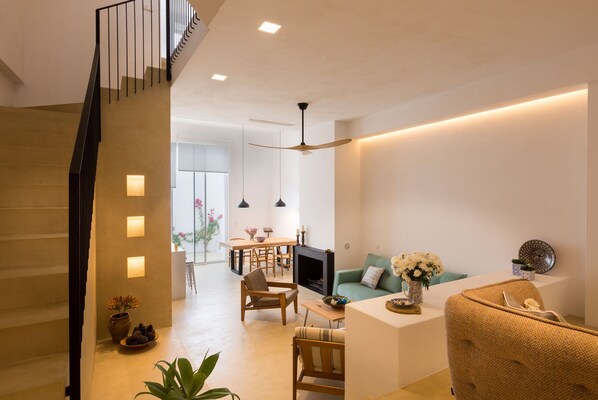 A modern living room with a staircase, a dining area, and a fireplace.