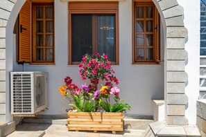 Ein Gebäude mit einem hölzernen Blumenkasten, gefüllt mit bunten Blumen, vor einem Fenster mit Holzklappläden.