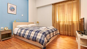 A bedroom with a bed, a nightstand, a TV, and a window with curtains. - Kolonaki Hill View Apartment (Athens)