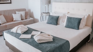 Een opgemaakt bed met een wit en blauwgroen dekbed, een bedlampje en een wit hoofdbord.