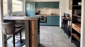 Una cocina moderna con armarios color turquesa, una isla de madera y un taburete negro.