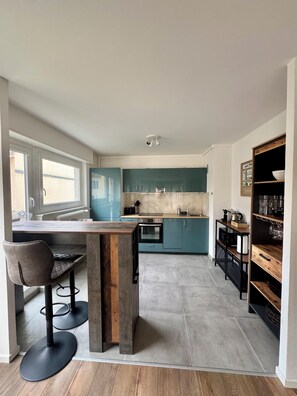 Una cucina moderna con armadietti color acquamarina, un'isola in legno e uno sgabello da bar nero.