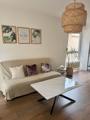 A modern living room with a sofa, a coffee table, and a hanging rattan light fixture.
