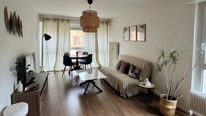Una sala de estar moderna con sofá, mesa de comedor y televisor.