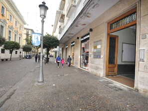 Una calle empedrada con tiendas, un farol y un edificio con un gran ventanal.