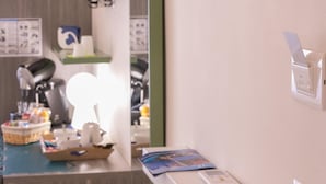 Un baño con espejo, lavamanos, toallero y estante con artículos de aseo.