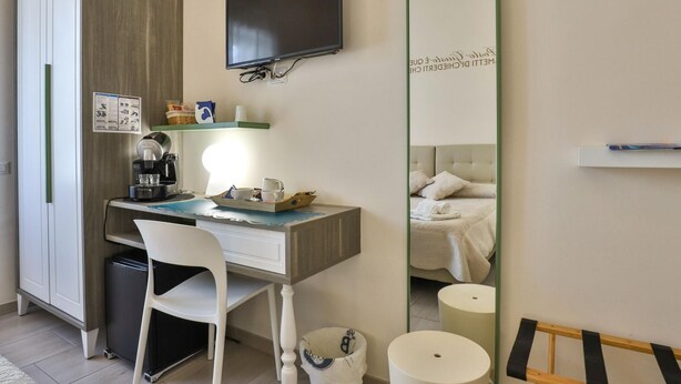 Una habitación de hotel con escritorio, silla y cama con cabecera. Hay un televisor montado en la pared sobre el escritorio.