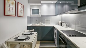 A compact kitchen with a built-in microwave, a sink, and a stove. There is a dining table with chairs and a small rug.