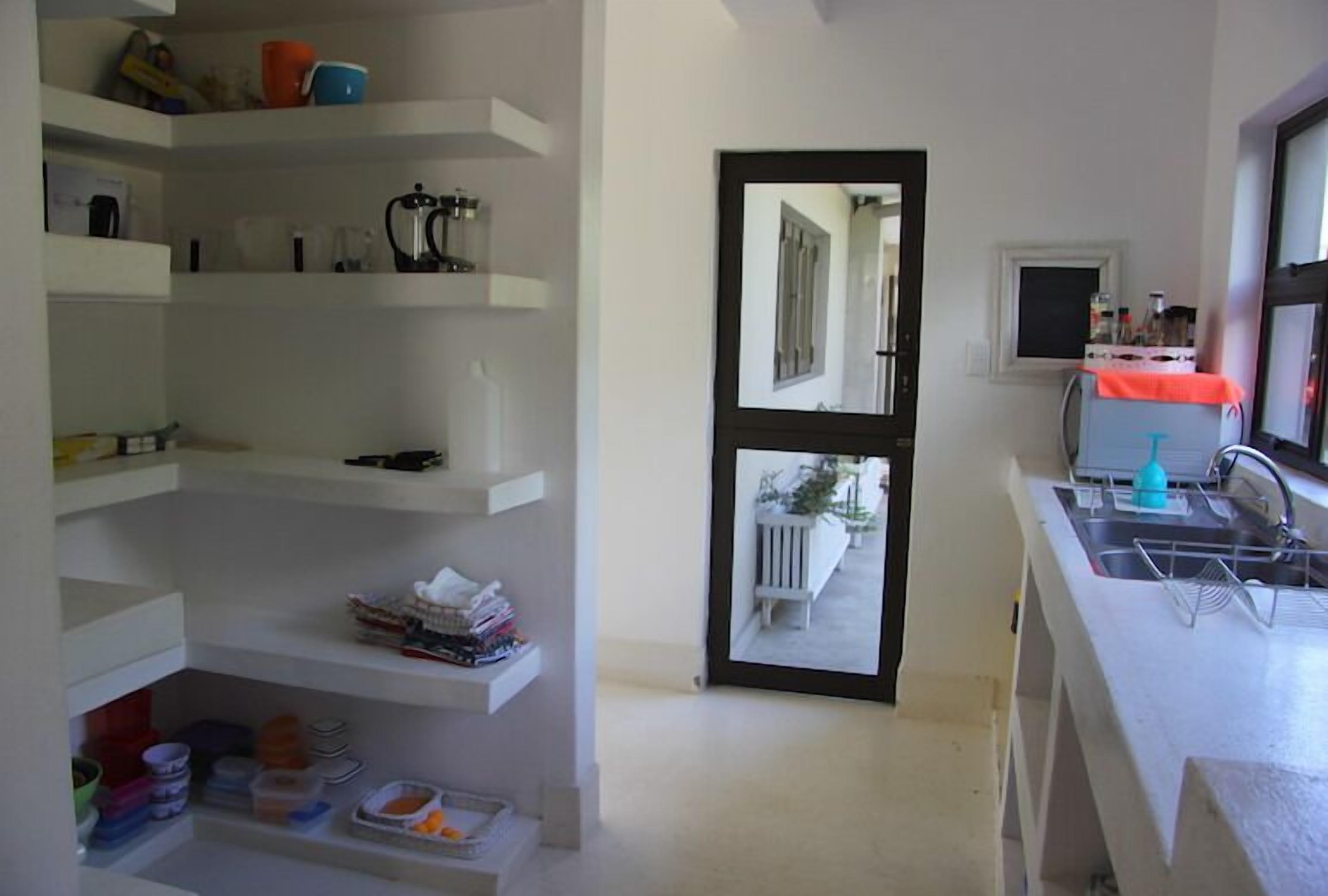A kitchen with white shelves, a sink, and a window.
