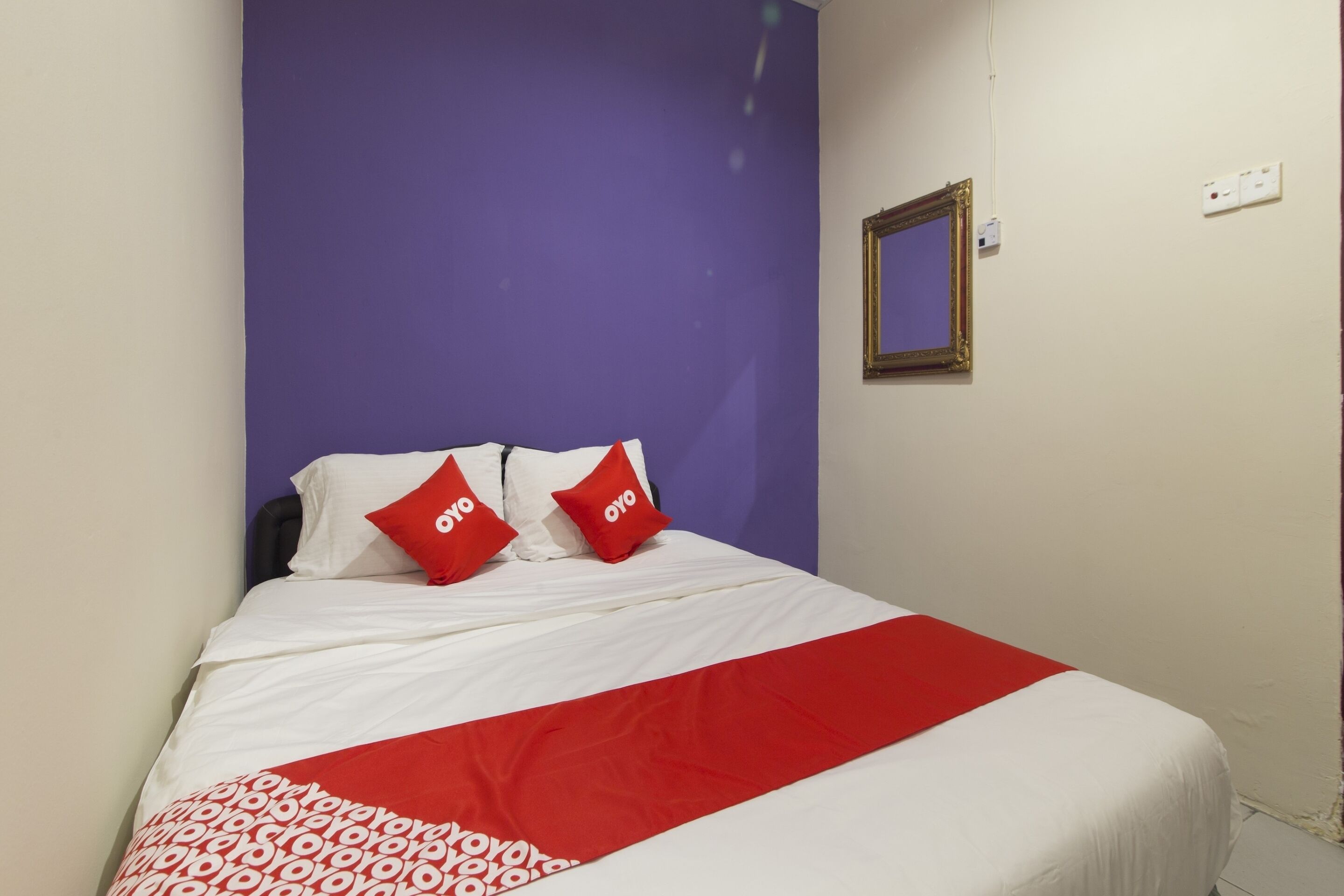 A bed with white and red bedding, two red pillows with the word "oyo" on them, and a red and white patterned blanket.