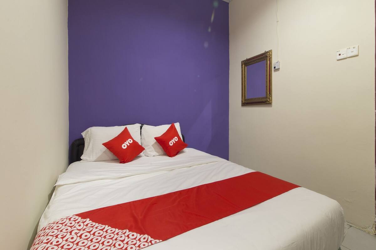 A bed with white and red bedding, two red pillows with the word "oyo" on them, and a red and white patterned blanket.