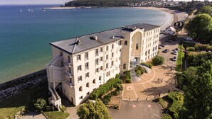 Un grande hotel a più piani con un cortile interno, situato vicino a una spiaggia e al mare.
