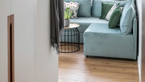 A modern living room with a light blue sofa, a round coffee table, and a green curtain. - Septa Studios (Thessaloniki)