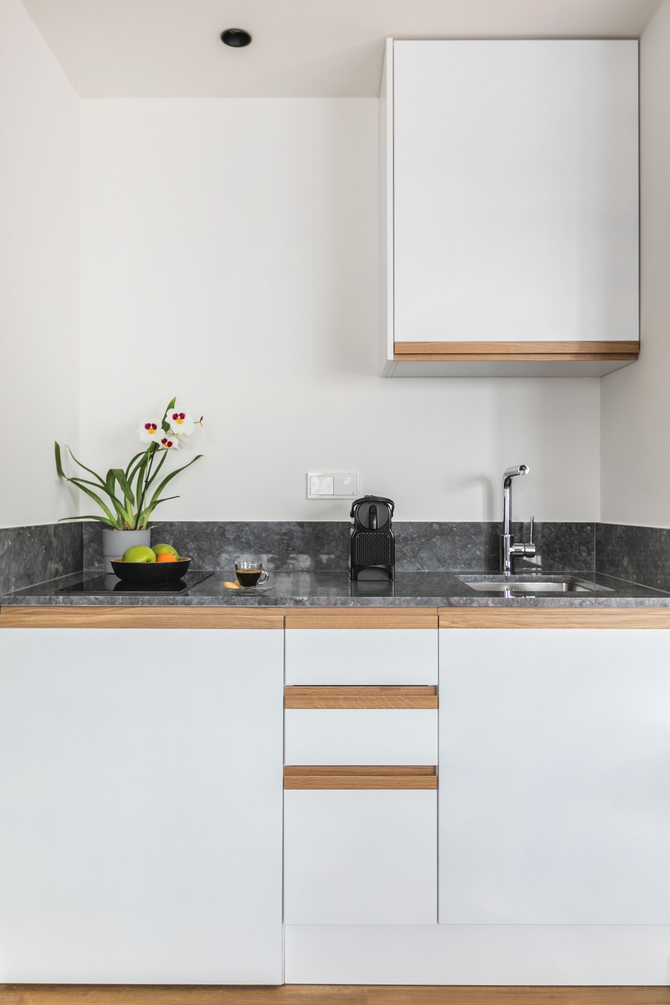 Een moderne keuken met een marmeren aanrecht, een spoelbak, een koffiezetapparaat en een potplant.