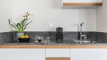 Een moderne keuken met een marmeren aanrecht, een spoelbak, een koffiezetapparaat en een potplant.