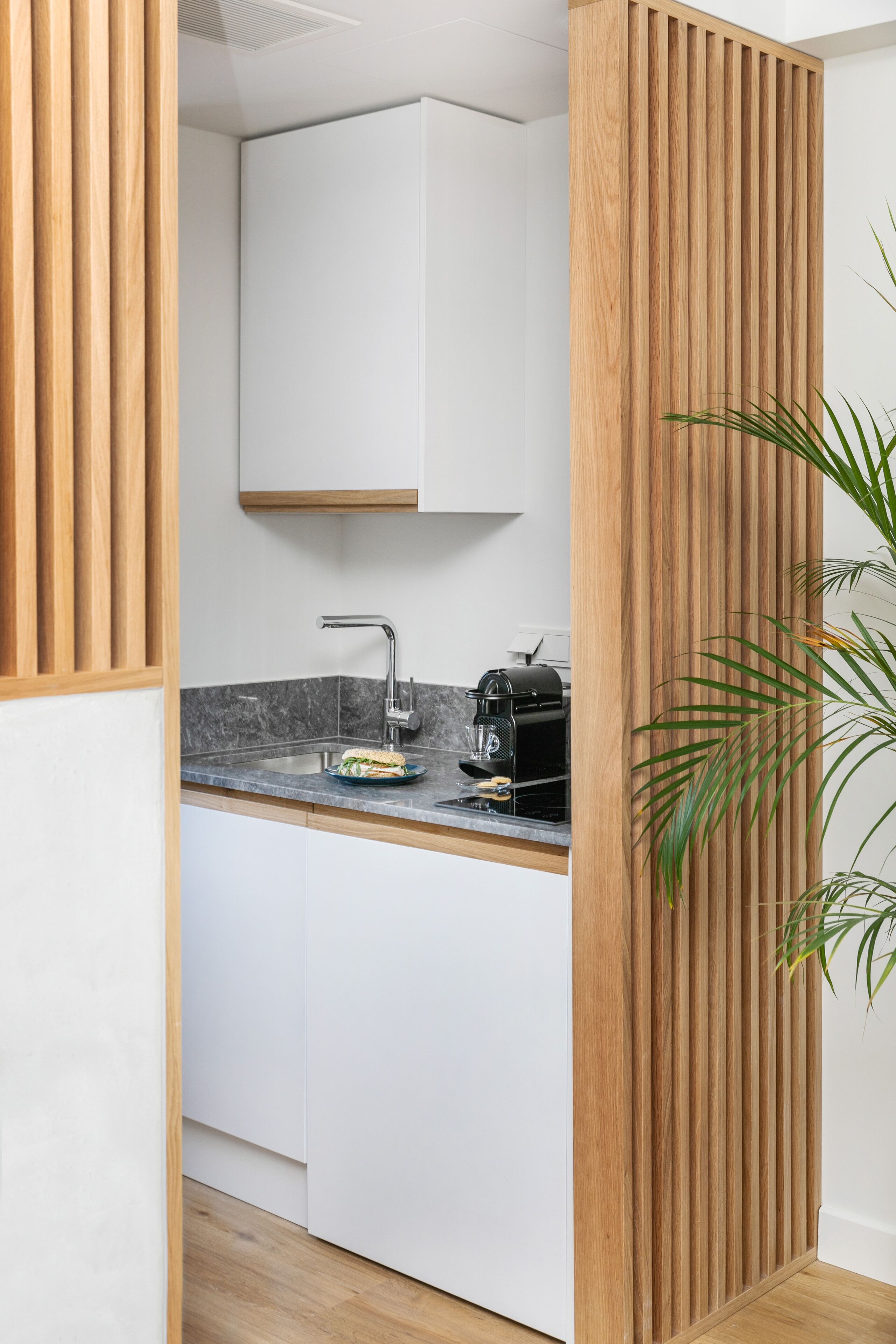 Una cocina moderna con separador de madera, horno empotrado y lavamanos.