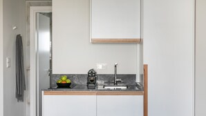 A compact kitchen with a sink, a bowl of fruit, and a kettle on the counter. - Septa Studios (Thessaloniki)