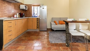 Una cocina compacta con protector mural de ladrillo, extractor de acero inoxidable, microondas y refrigerador.