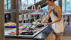 A buffet setup with various food items and a person serving.