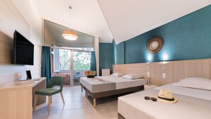 Habitación de hotel con escritorio, dos camas, televisión y vista al exterior.