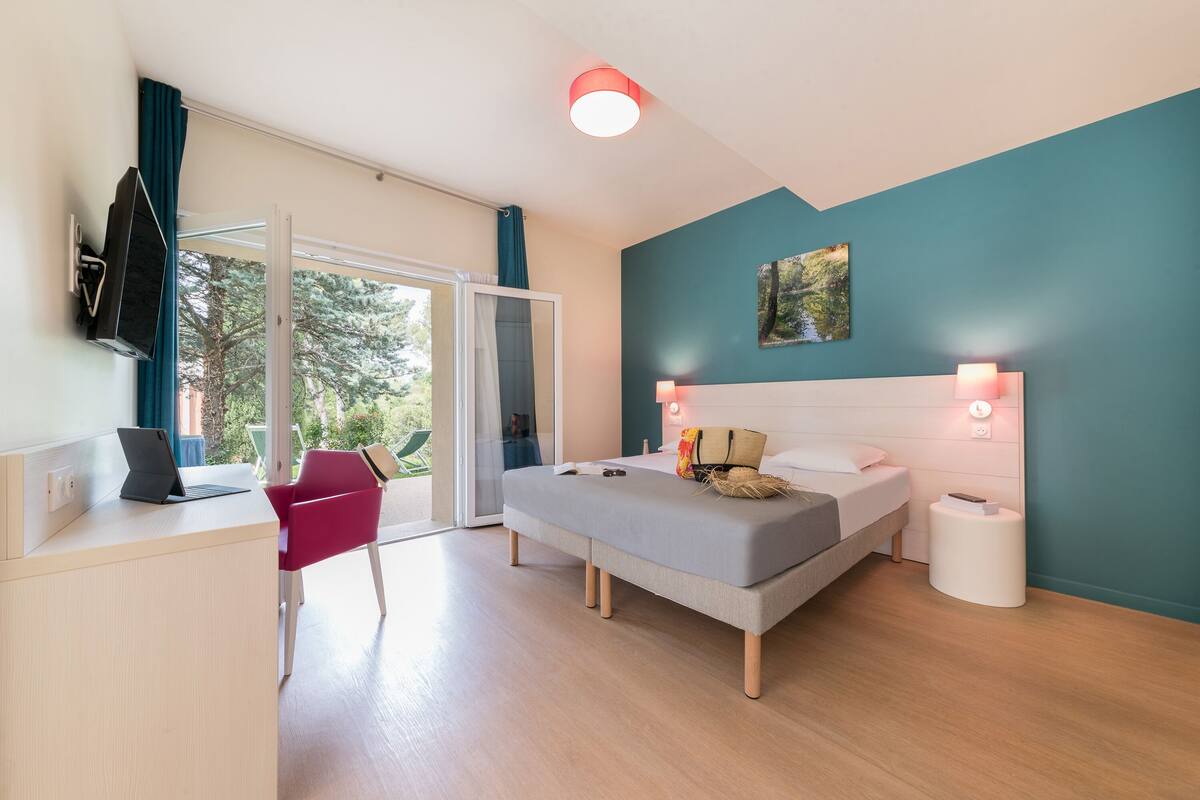 Une chambre à coucher moderne avec un lit, des lampes de chevet, un bureau avec un ordinateur portable et une chaise.