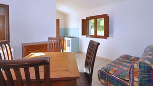 A compact living space with a dining area, kitchenette, and a small sofa. - Residence a Badesi ID 3372 (Badesi)
