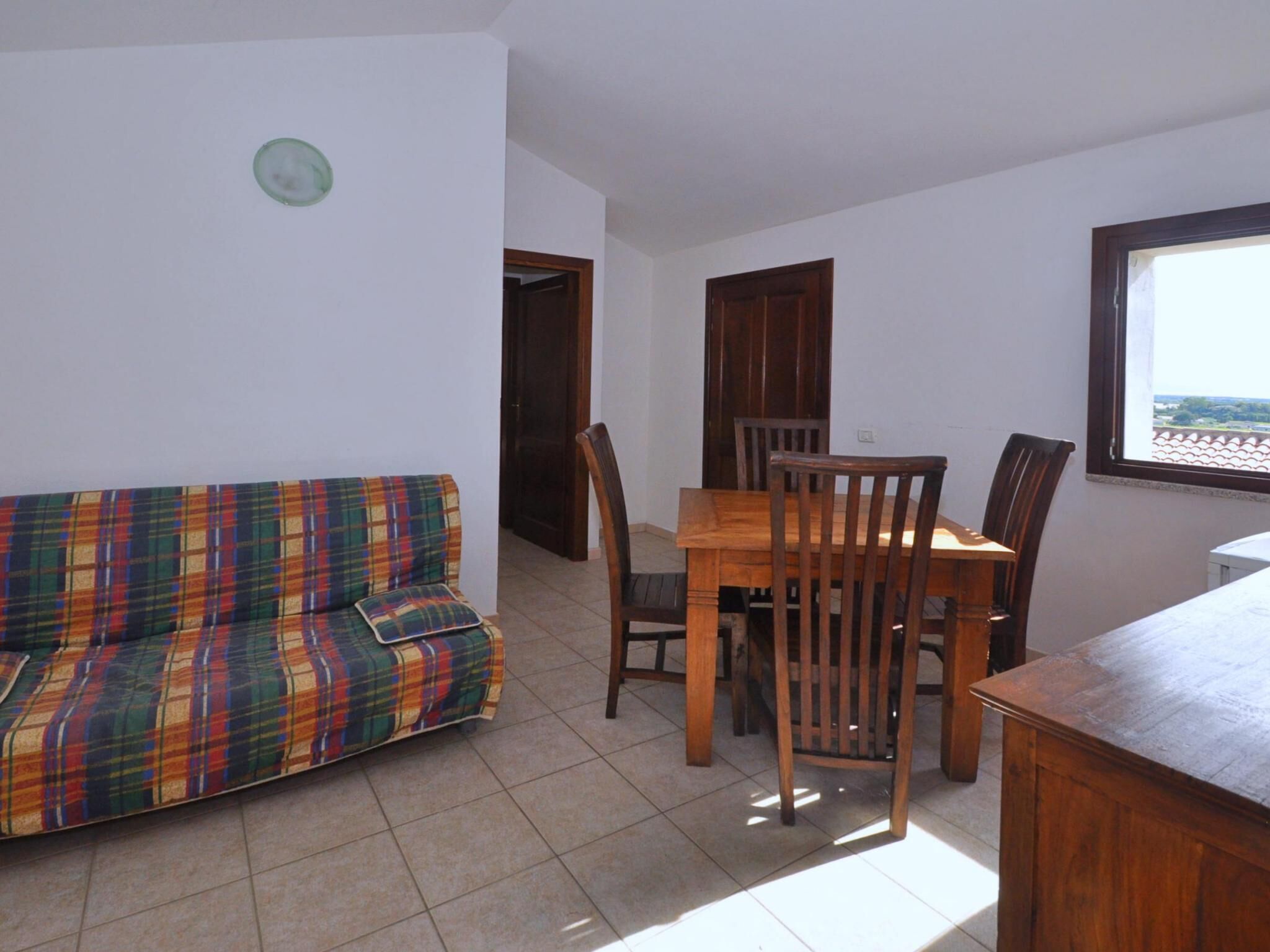 Una habitación con un sofá escocés, una mesa de comedor de madera y sillas.