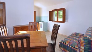 Een ruimtelijk ingerichte leefruimte met een eethoek, kitchenette en een kleine zithoek.