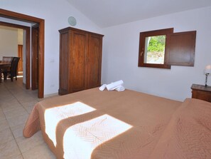 A bedroom with a bed, a wardrobe, a window, and a door leading to a dining area.