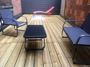 A patio with a wooden deck, a small table, and two chairs.