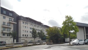 Ein mehrgeschossiges Gebäude mit flacher Fassade, einer Fußgängerüberweg und geparkten Autos.