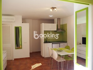 Una cocina compacta con armarios blancos, una encimera negra y un salpicadero verde. Cuenta con una mesa de comedor y cuatro sillas.
