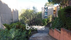 A narrow alleyway with a stone wall on one side and a building with balconies on the other. - COZY APARTMENT WITH AIR CONDITIONING & COMMUNAL SWIMMING POOL IN LOS PINOS (Platja d'Aro)