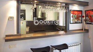 Een moderne keuken met een ingebouwde wijnrek, een digitale thermostaat en een ingelijst advertentie voor Estrella Damm bier.
