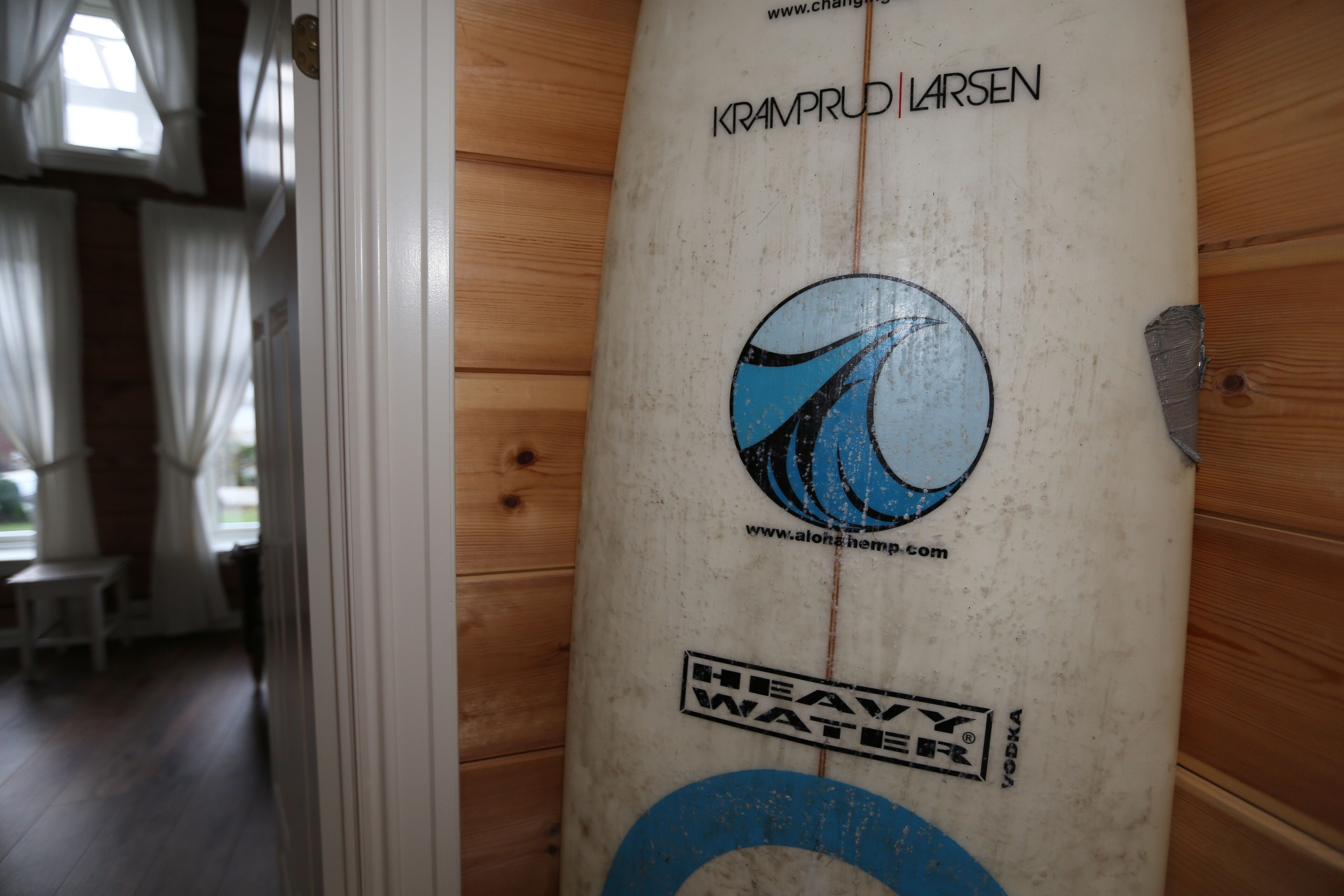 Ein Surfbrett mit dem Text "KRAMPRUD LARSEN" und "HEAVY WATER".