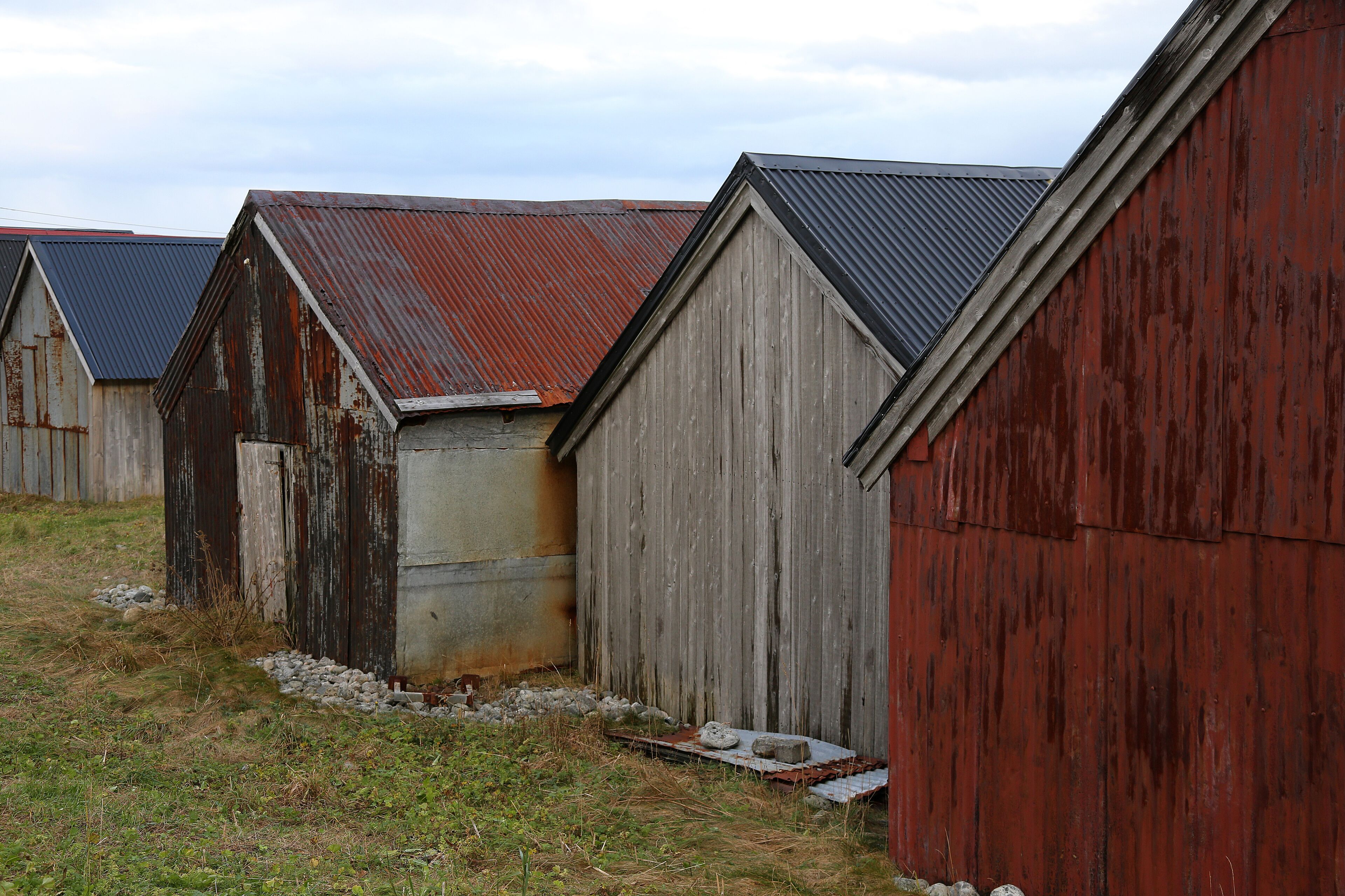 A row of wooden buildings with metal roofs, some with visible rust and wear.
