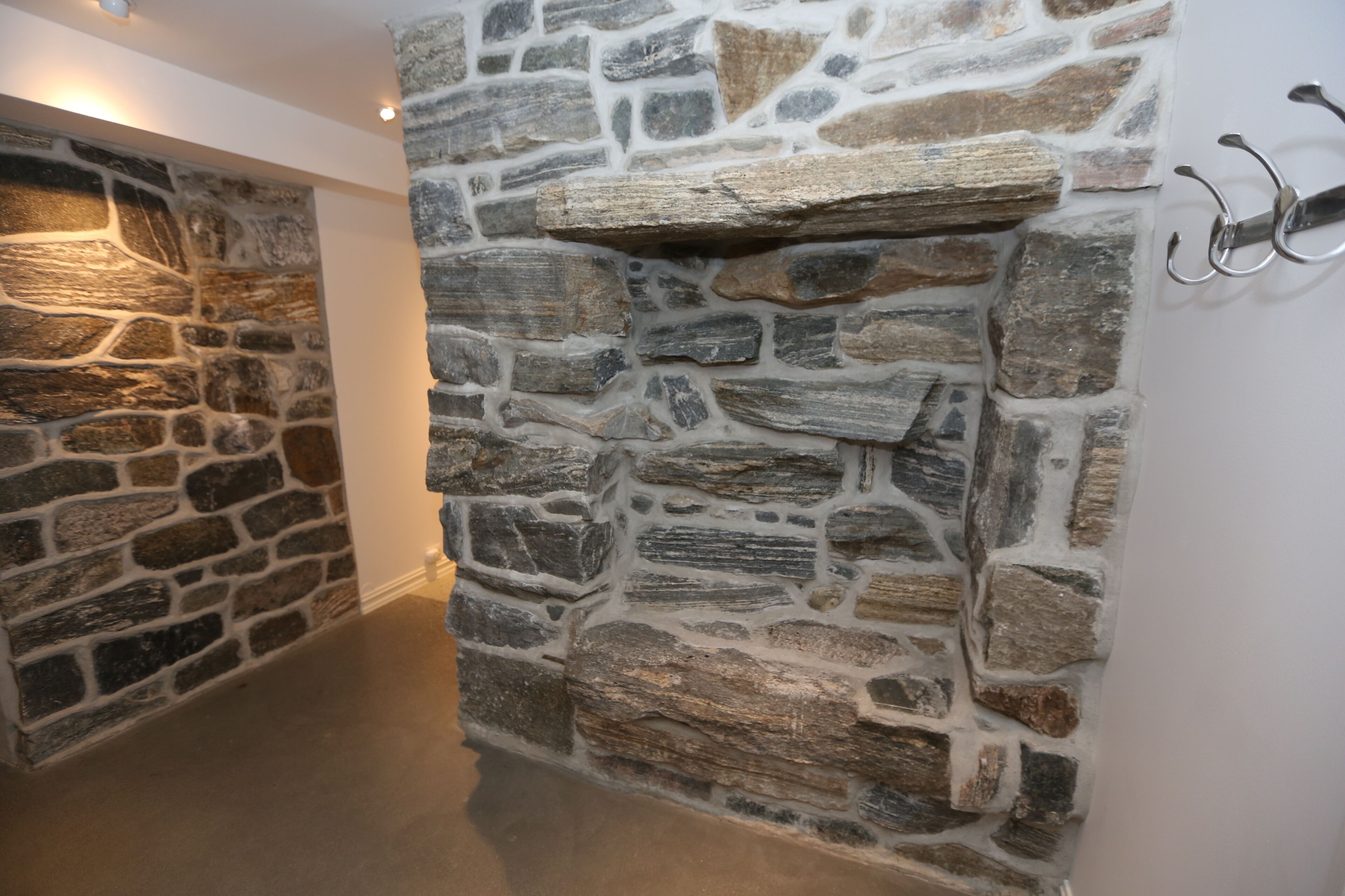 A stone wall with a built-in shelf and hooks on the right side.