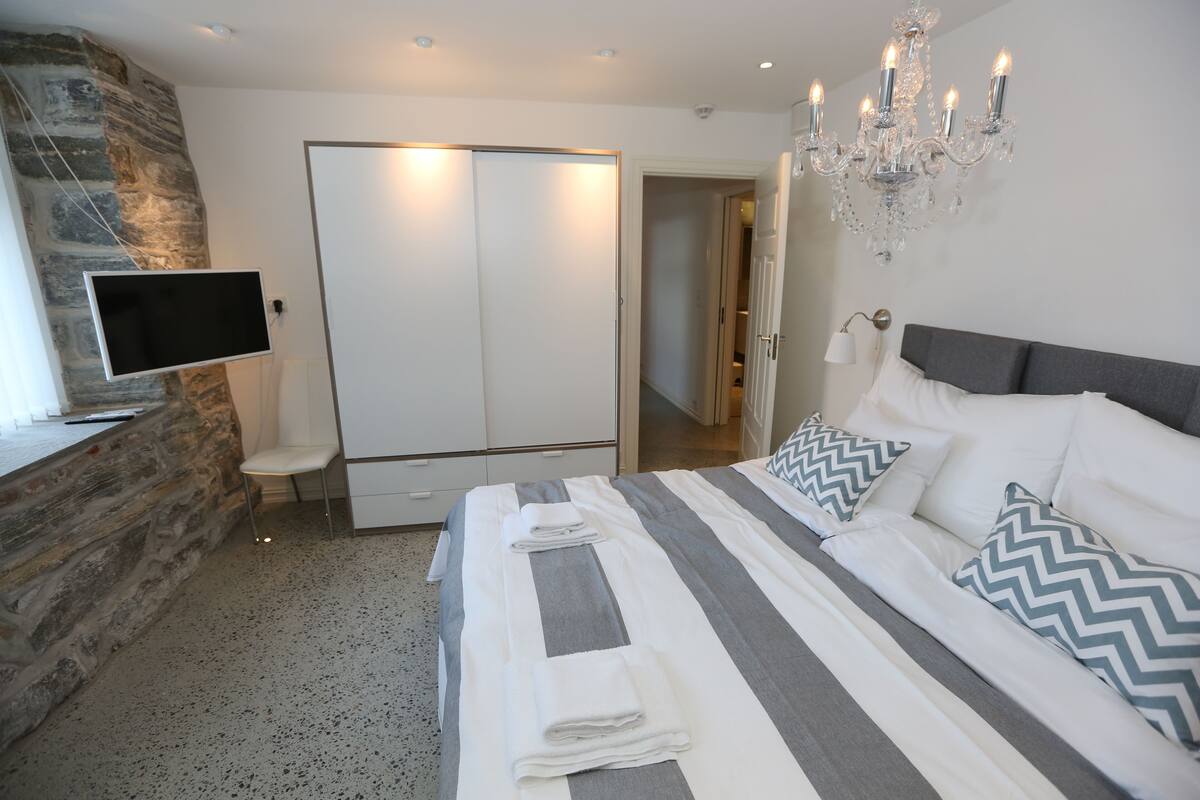 Quarto com cama, televisão, guarda-roupa e candelabro.