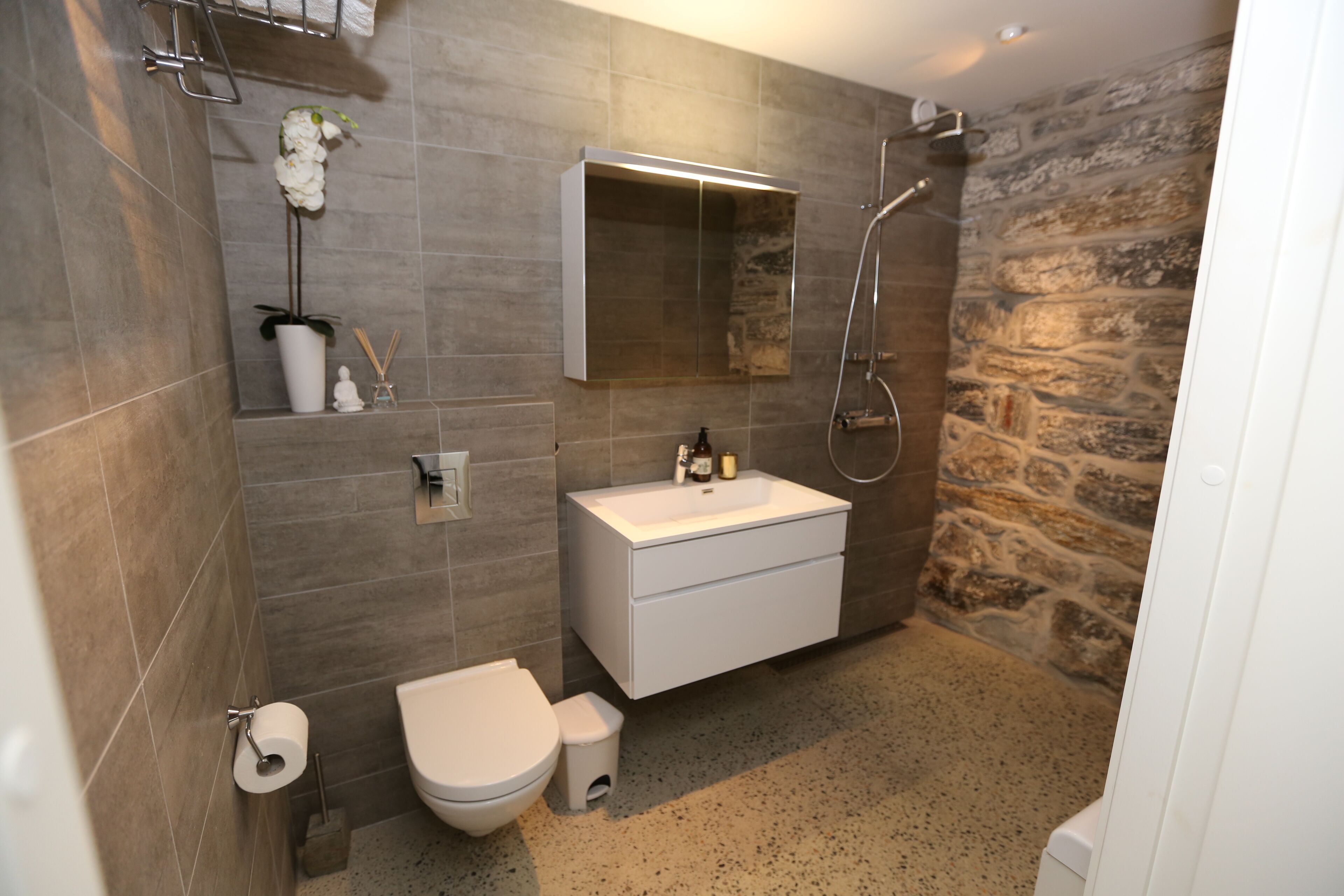 A modern bathroom with a toilet, sink, and shower.