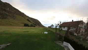 A rural landscape with a house, a grassy field, and a hill.