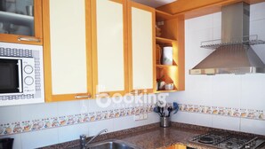 A kitchen with wooden cabinets, a microwave, a gas stove, and a stainless steel sink. - APARTMENT WITH 3 ROOMS AND LARGE TERRACE, 5 MIN. FROM THE BEACH, IN THE CENTER (Platja d'Aro)