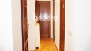 A hallway with wooden doors, a white wall, and a tiled floor. - APARTMENT WITH 3 ROOMS AND LARGE TERRACE, 5 MIN. FROM THE BEACH, IN THE CENTER (Platja d'Aro)