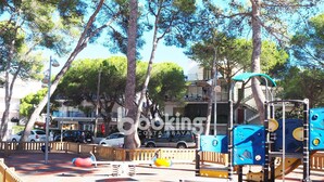 A playground with climbing structures and slides, surrounded by trees and a wooden fence. - APARTMENT WITH 3 ROOMS AND LARGE TERRACE, 5 MIN. FROM THE BEACH, IN THE CENTER (Platja d'Aro)
