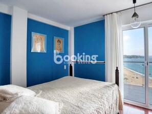Ein Schlafzimmer mit einem großen Bett, Meerblick und zwei gerahmten Kunstwerken an der Wand.