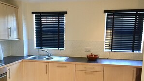 A kitchen with two windows, a sink, and wooden cabinets. - Modern 2 Bed Apartment in Southampton (Southampton)
